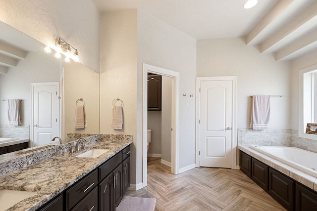 bathroom featuring a garden tub, double vanity, baseboards, and a sink