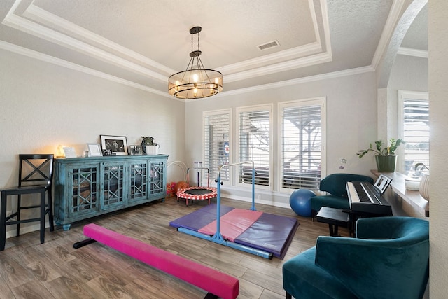 workout room with visible vents, a raised ceiling, a notable chandelier, and plenty of natural light