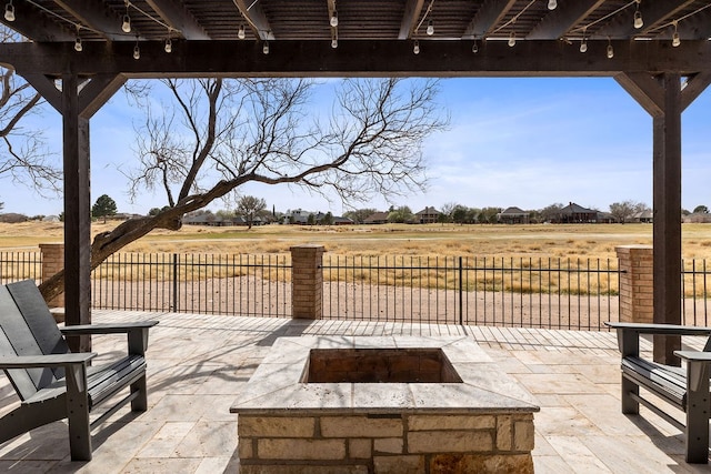 view of patio / terrace with a rural view, fence, and an outdoor fire pit