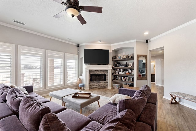 living area with visible vents, a textured ceiling, ornamental molding, and light wood finished floors