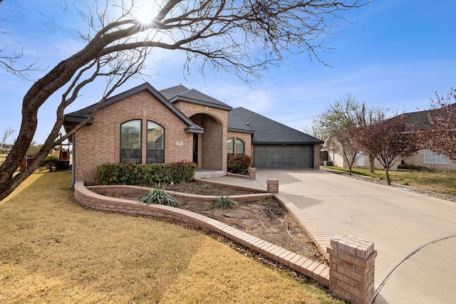 view of front of house featuring brick siding, concrete driveway, a front yard, roof with shingles, and an attached garage