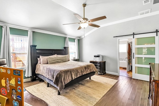 bedroom featuring crown molding, vaulted ceiling, dark hardwood / wood-style flooring, ceiling fan, and a barn door