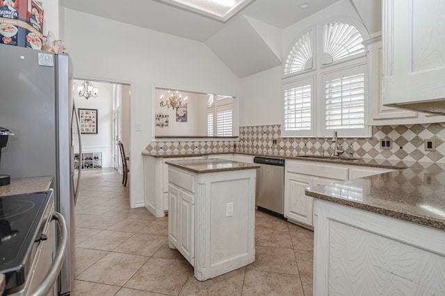 kitchen featuring sink, dark stone countertops, appliances with stainless steel finishes, a kitchen island, and backsplash