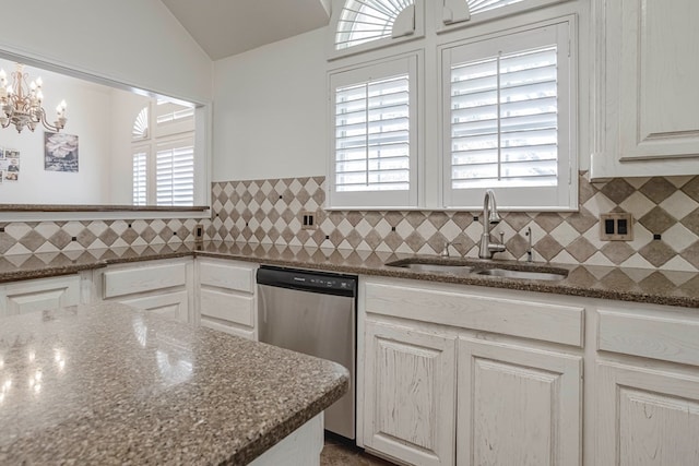 kitchen featuring white cabinetry, sink, stainless steel dishwasher, and dark stone counters