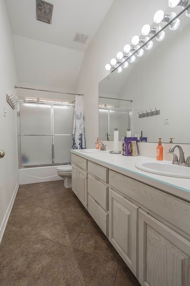 full bathroom featuring tile patterned floors, toilet, combined bath / shower with glass door, vaulted ceiling, and vanity