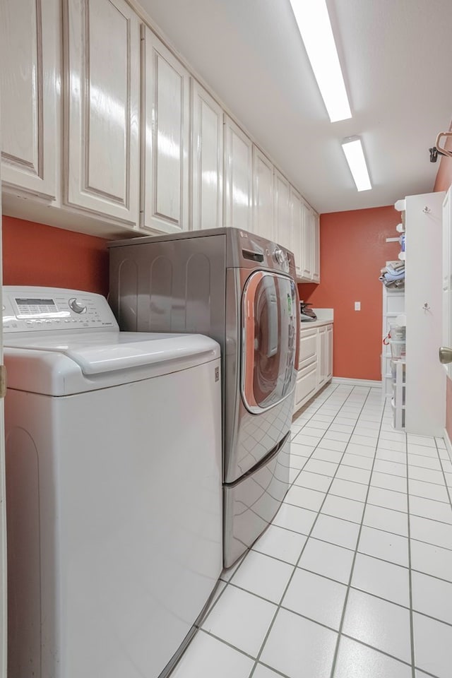 laundry area featuring washing machine and dryer, cabinets, and light tile patterned flooring