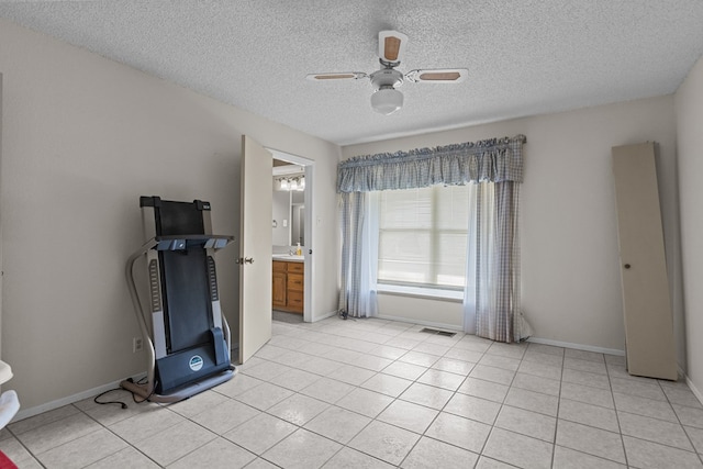 interior space with ceiling fan, light tile patterned flooring, and a textured ceiling