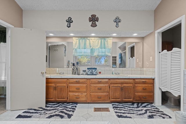 bathroom with tile patterned flooring, vanity, and a textured ceiling