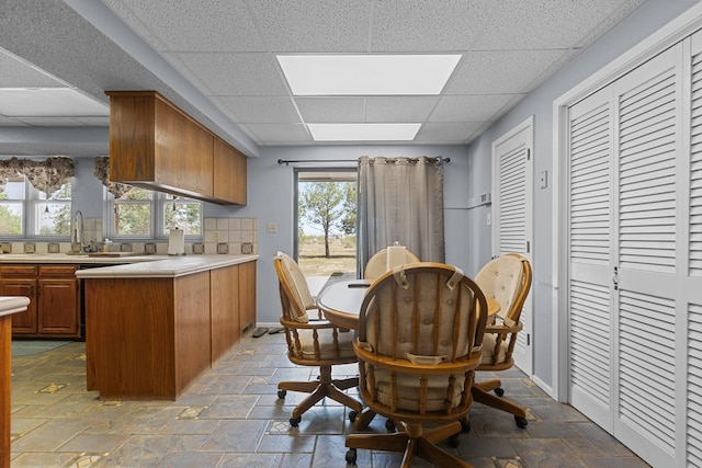 kitchen featuring a drop ceiling, a healthy amount of sunlight, kitchen peninsula, and sink