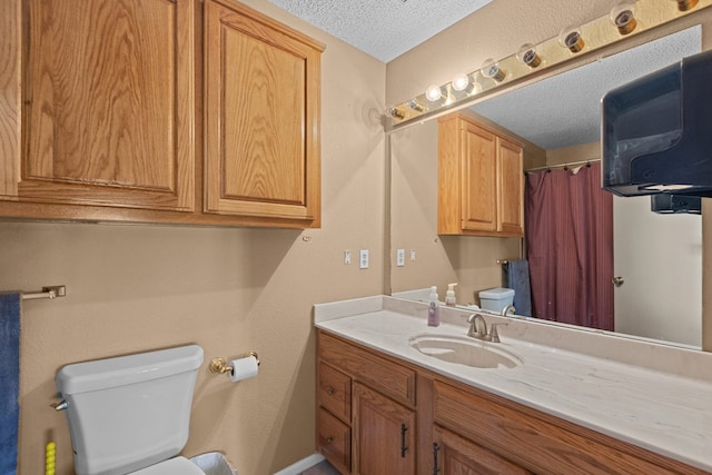 bathroom with vanity, a textured ceiling, and toilet