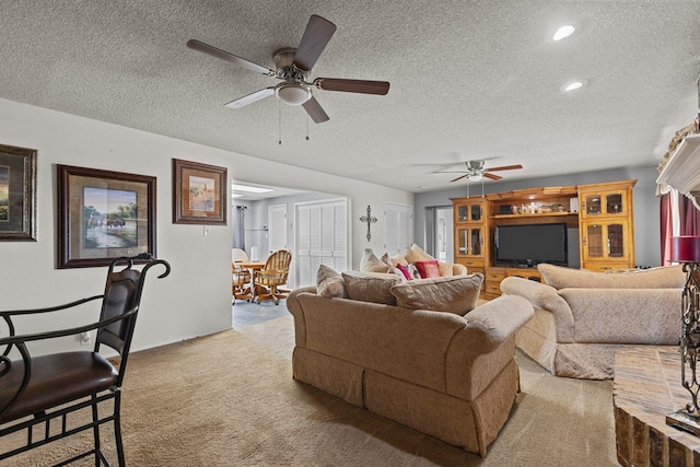 living room featuring ceiling fan, light colored carpet, and a textured ceiling