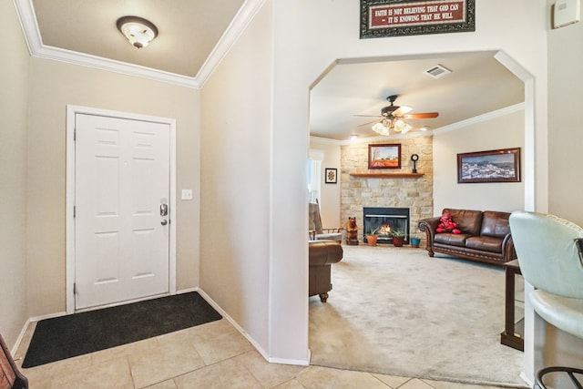 foyer with crown molding, light colored carpet, a fireplace, and ceiling fan