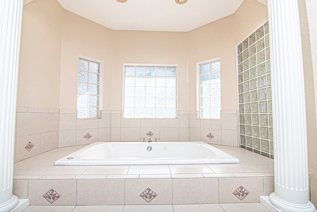 bathroom with a relaxing tiled tub and a healthy amount of sunlight