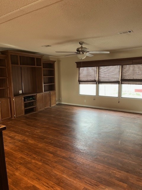 unfurnished living room with ceiling fan, dark hardwood / wood-style floors, and a textured ceiling