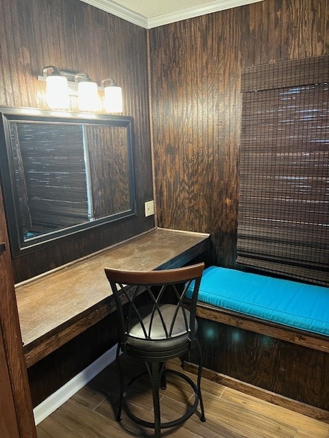 sitting room with wood-type flooring, wooden walls, and crown molding