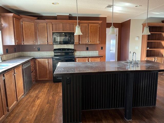 kitchen with dark wood-type flooring, a kitchen island with sink, hanging light fixtures, and black appliances