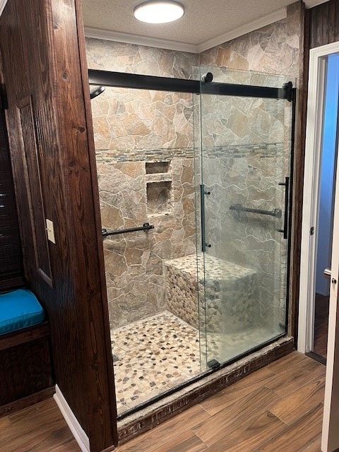 bathroom featuring wood-type flooring, ornamental molding, a textured ceiling, and walk in shower