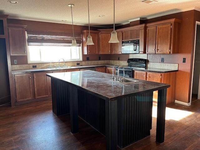 kitchen with sink, a center island with sink, a kitchen breakfast bar, and black appliances