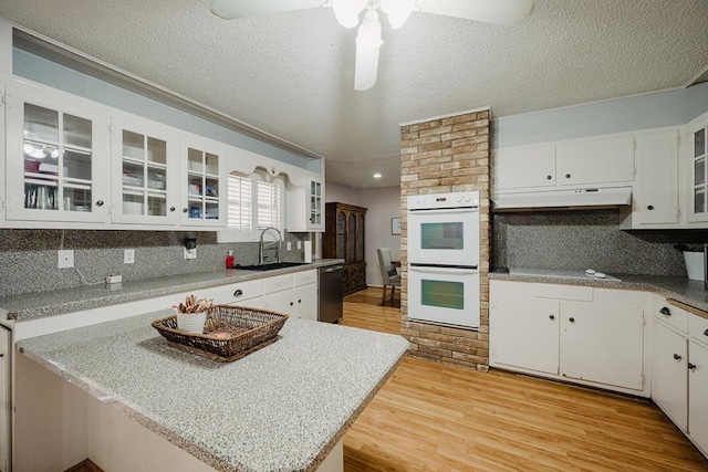 kitchen featuring light hardwood / wood-style flooring, dishwasher, white double oven, sink, and white cabinetry