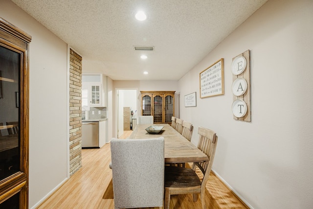 dining space with a textured ceiling and light hardwood / wood-style flooring