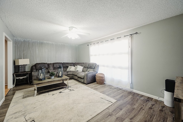 living room with a textured ceiling, hardwood / wood-style floors, and ceiling fan