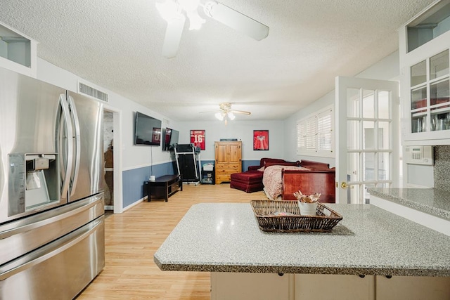 kitchen featuring light wood-type flooring, a textured ceiling, stainless steel fridge with ice dispenser, and ceiling fan