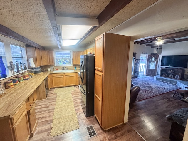 kitchen featuring ceiling fan, sink, black fridge, and light hardwood / wood-style flooring