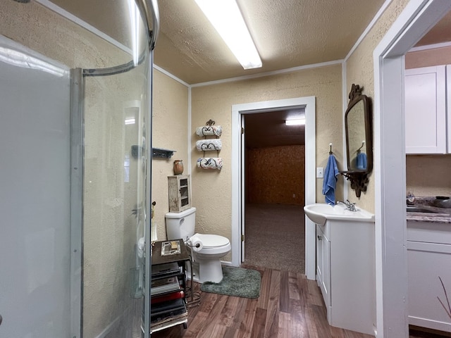 bathroom featuring hardwood / wood-style floors, a shower with door, vanity, toilet, and crown molding