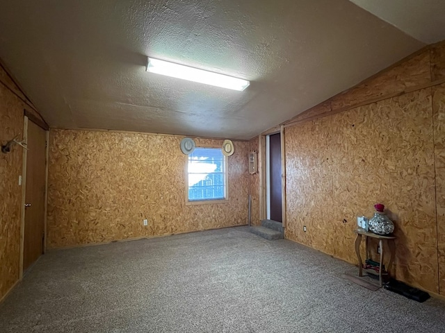 carpeted spare room with vaulted ceiling and a textured ceiling