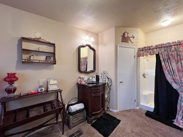 bathroom with a textured ceiling, a shower, and vanity