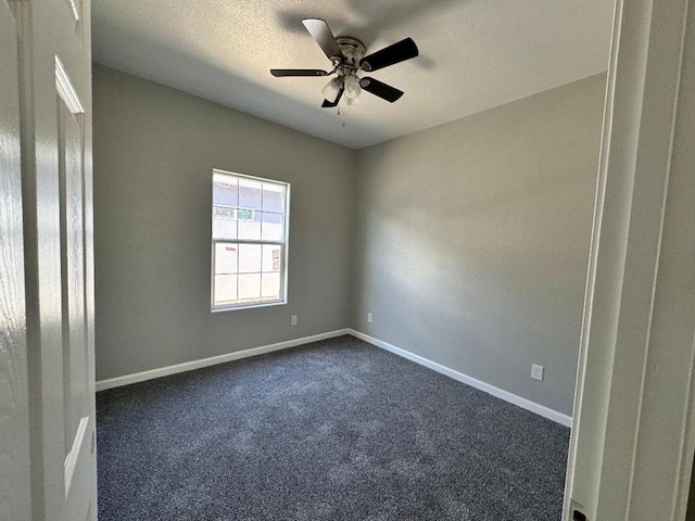 spare room featuring a textured ceiling, dark carpet, a ceiling fan, and baseboards