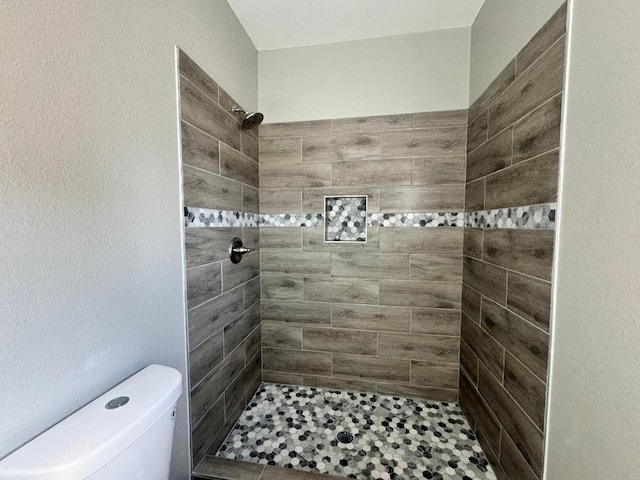 bathroom with tiled shower and toilet