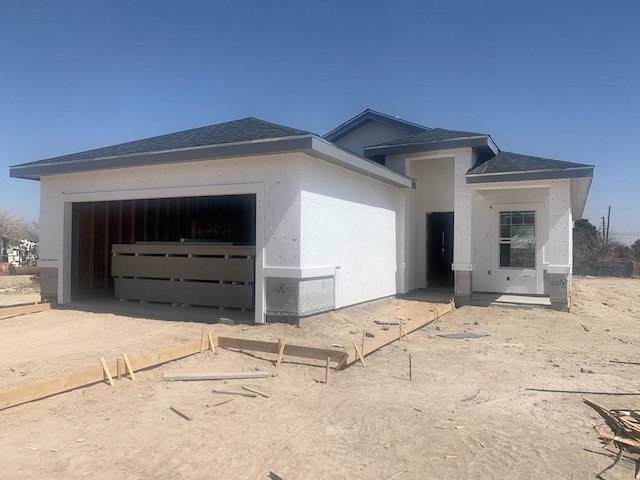 view of front of house featuring driveway, a shingled roof, an attached garage, and stucco siding