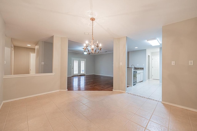 spare room featuring light tile patterned floors, a notable chandelier, and french doors