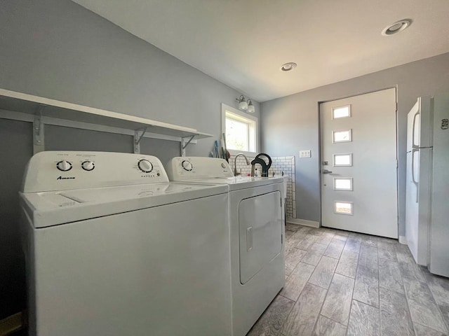 laundry room with washing machine and clothes dryer and light hardwood / wood-style floors