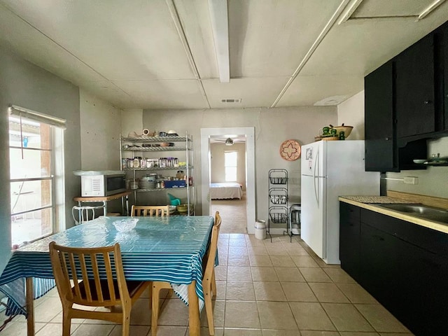 dining space with ceiling fan, light tile patterned flooring, and sink