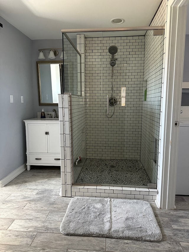 bathroom featuring vanity, a shower with shower door, and washer / dryer