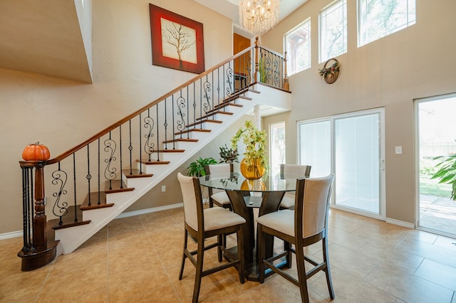 tiled dining area with a healthy amount of sunlight, a high ceiling, and a chandelier