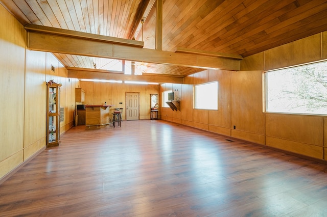 interior space featuring lofted ceiling with beams, wood-type flooring, and wooden walls