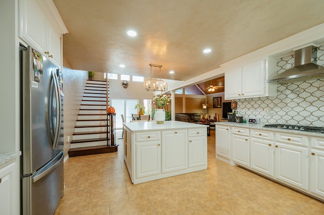 kitchen with stainless steel appliances, a kitchen island, white cabinetry, and wall chimney exhaust hood