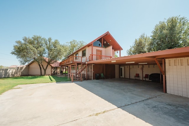 back of house featuring a carport, a wooden deck, and a lawn