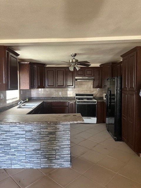 kitchen with sink, black fridge, kitchen peninsula, dark brown cabinets, and white stove