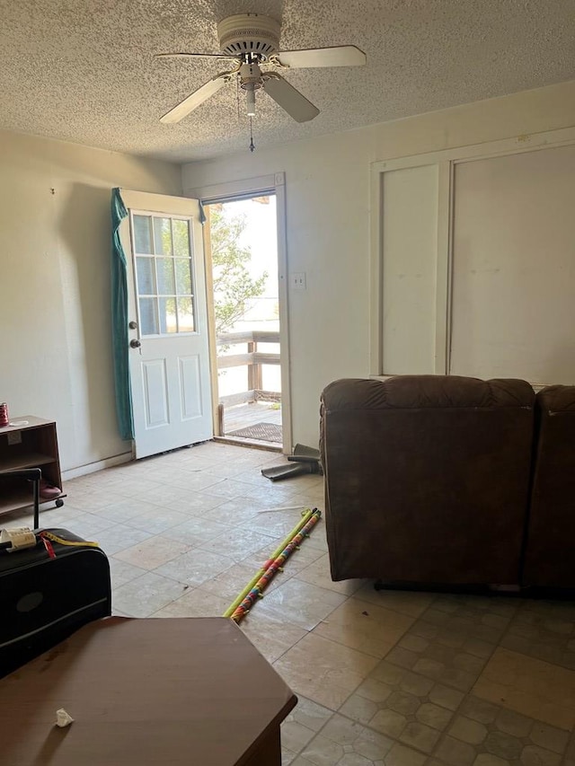 living room with ceiling fan and a textured ceiling