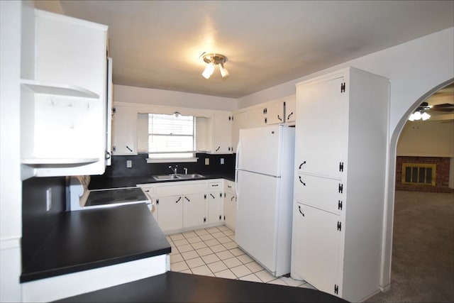 kitchen with light tile patterned flooring, sink, stainless steel range, white fridge, and white cabinetry