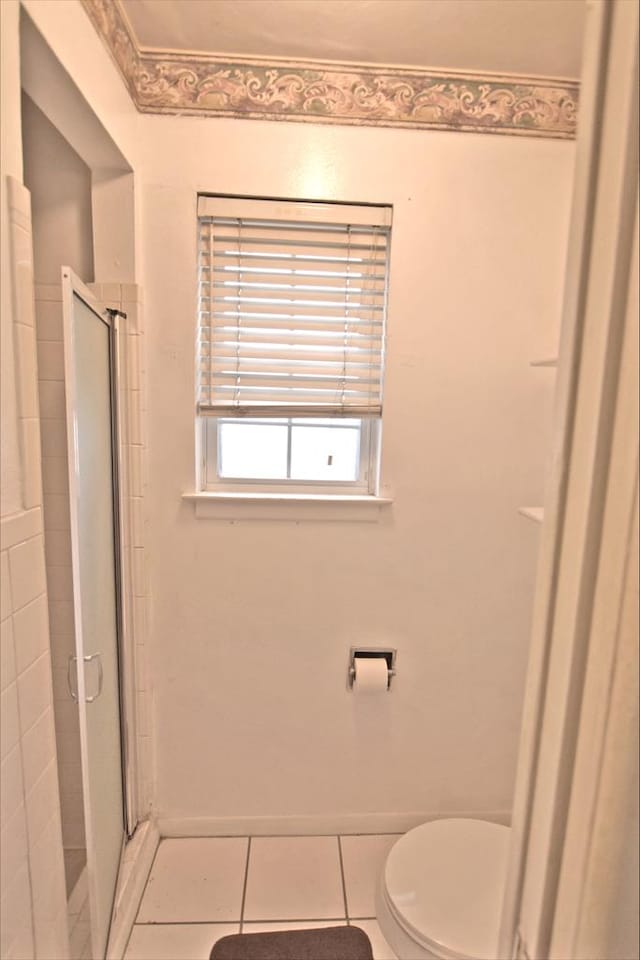 bathroom featuring tile patterned flooring, toilet, and walk in shower