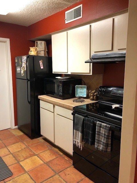 kitchen with black appliances, white cabinets, backsplash, and a textured ceiling