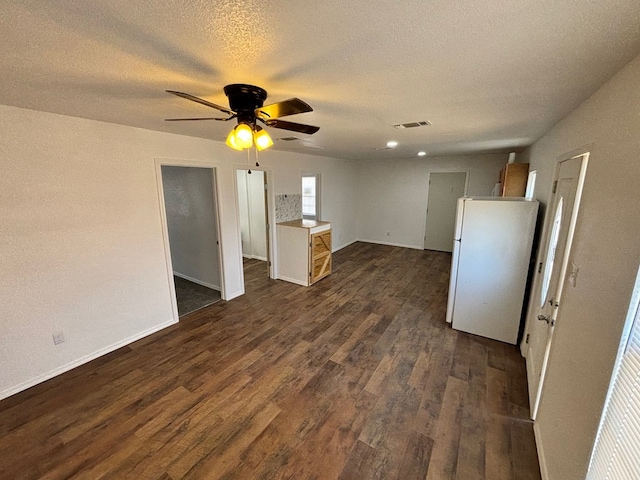 unfurnished living room featuring ceiling fan, dark wood-type flooring, and a textured ceiling