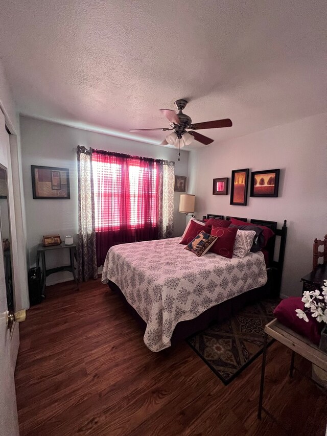 bedroom with a textured ceiling, ceiling fan, and dark wood-type flooring