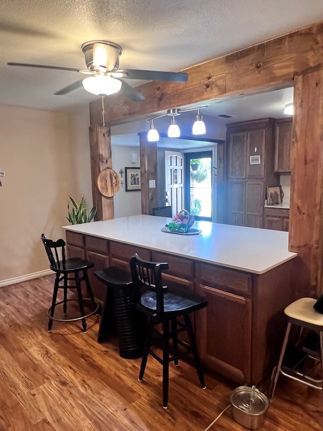 kitchen featuring ceiling fan, hanging light fixtures, kitchen peninsula, hardwood / wood-style floors, and a textured ceiling