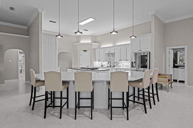 kitchen with white cabinetry, stainless steel fridge, a kitchen island, and decorative light fixtures